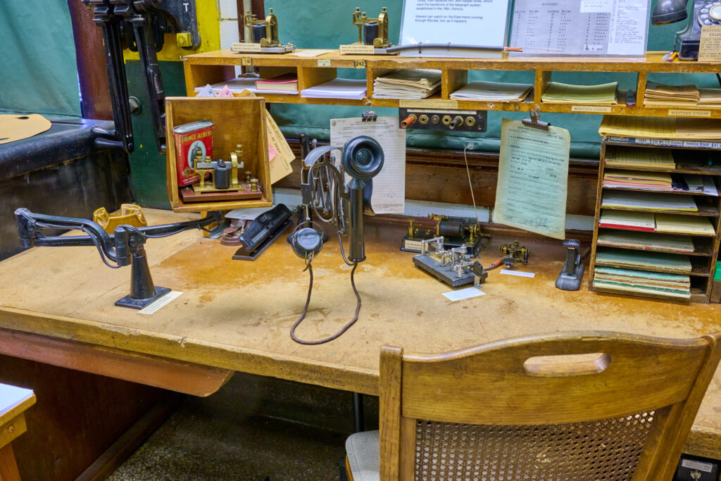 Wooden desk with a telegraph machine mounted to the top.
